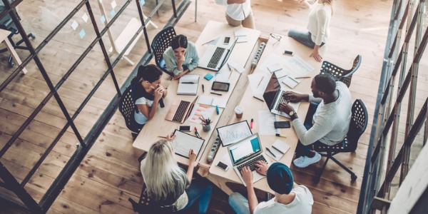 Seven employees working around a large desk in an office space.
