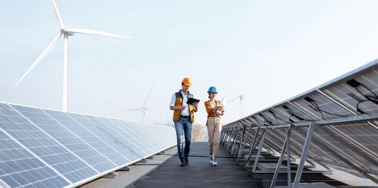 A solar power site with a renewable energy construction manager and an engineer walking and examining the placement of solar panels.