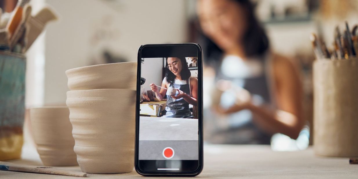 A TikTok creator recording herself painting a clay pot.